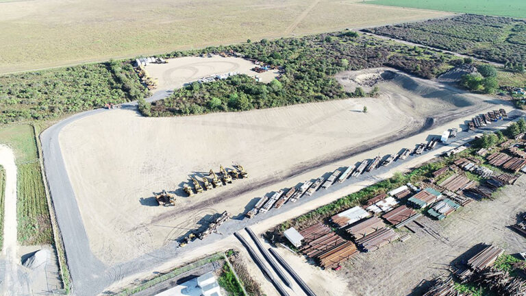 Aerial view of a graded yard and staging area at the Alpine Site Services site in Edna, TX, with equipment and material stockpiles, by Keeton Construction Services