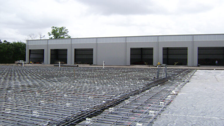 Reinforcing steel grid in front of a metal building at Master Rig International in Houston, TX by Keeton Construction Services showing open overhead doors
