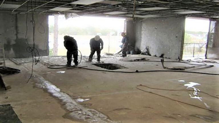 American Spectrum interior during construction, Houston, TX - Keeton Construction Services crew working on the bare slab with stripped walls and ceiling