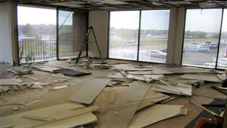 American Spectrum interior during demolition, Houston, TX - Keeton Construction Services debris on the floor and an open ceiling grid with large windows