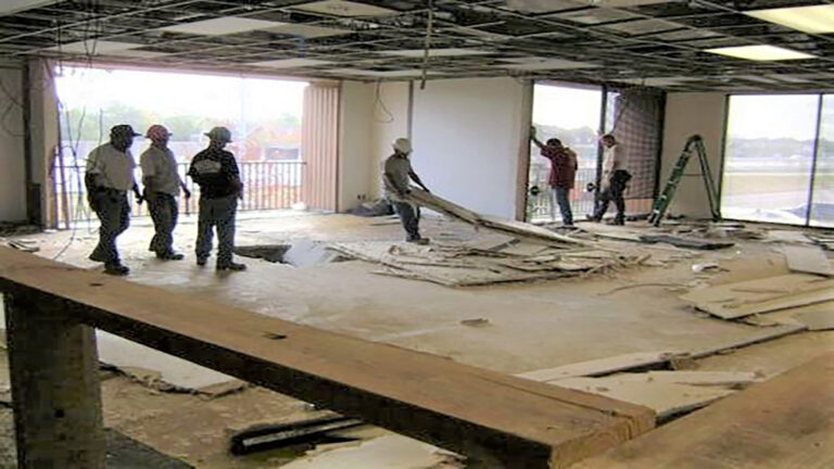 American Spectrum interior during demolition, Houston, TX - Keeton Construction Services workers removing debris from the floor