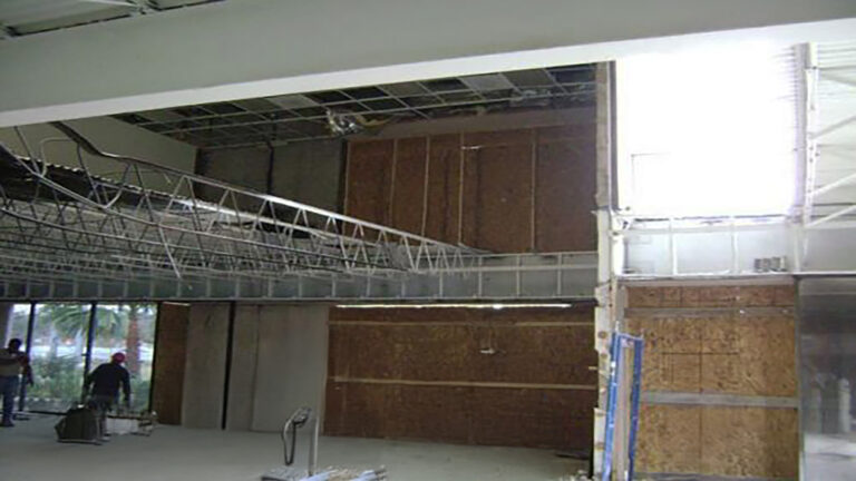 American Spectrum interior during construction, Houston, TX - Keeton Construction Services exposed wall framing and partial ceiling grid with workers near the entry