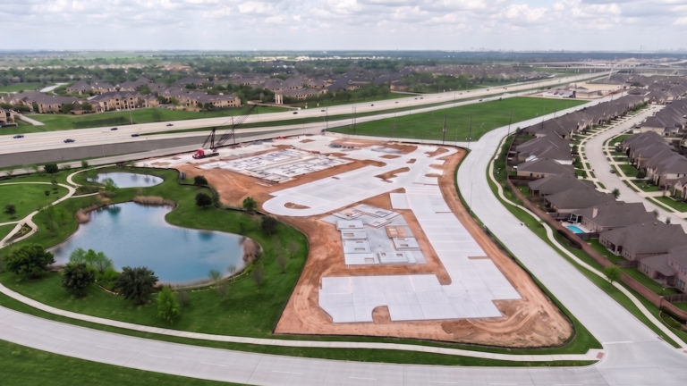 Aerial view of Bella Piazza Retail Center site during construction with crane and concrete slabs, Richmond, TX - Keeton Construction Services
