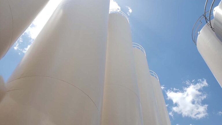 Ground-level upward view of Borden Dairy silos against blue sky in Houston, TX - Keeton Construction Services