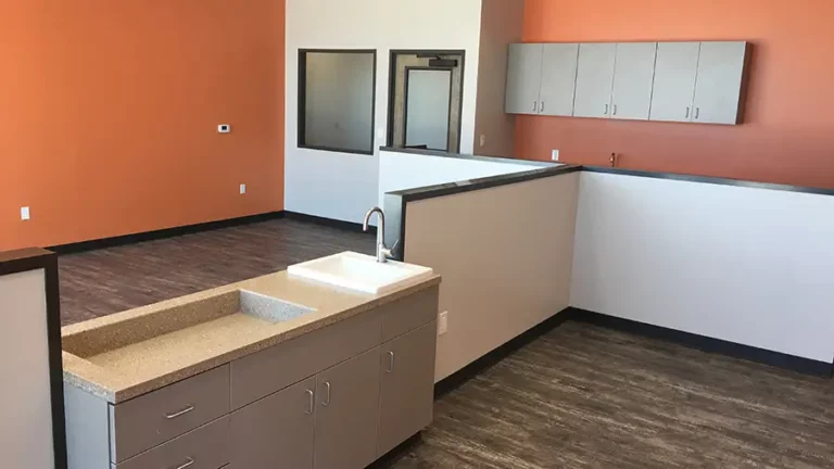Interior room at The Childhood Center in Katy, TX by Keeton Construction Services, showing cabinets with sink and orange accent walls