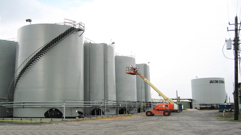 Jacob Stern and Son industrial tank farm in Houston, TX - boom lift alongside large storage tanks, work in progress, by Keeton Construction Services