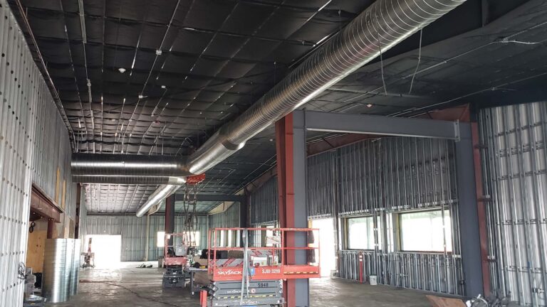 Ewald Kubota Equipment Dealership Houston TX - interior during construction with framing, scissor lift, and ductwork installation, by Keeton Construction Services