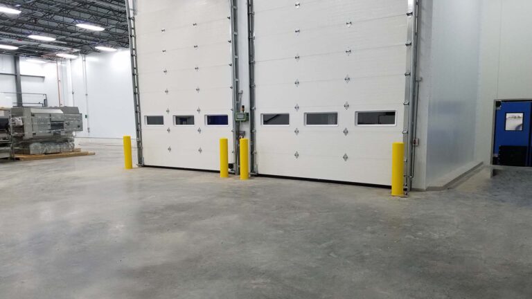 Interior view of overhead sectional doors at Renaissance Food Group, Houston, TX by Keeton Construction Services, with yellow bollards and concrete floor