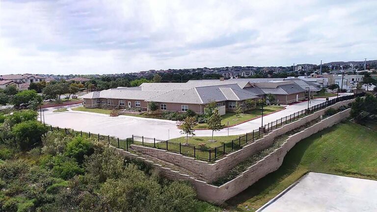 Aerial view of Autumn Leaves Memory Care in San Antonio, TX showing the building exterior, parking area, and perimeter retaining wall - Keeton Construction Services