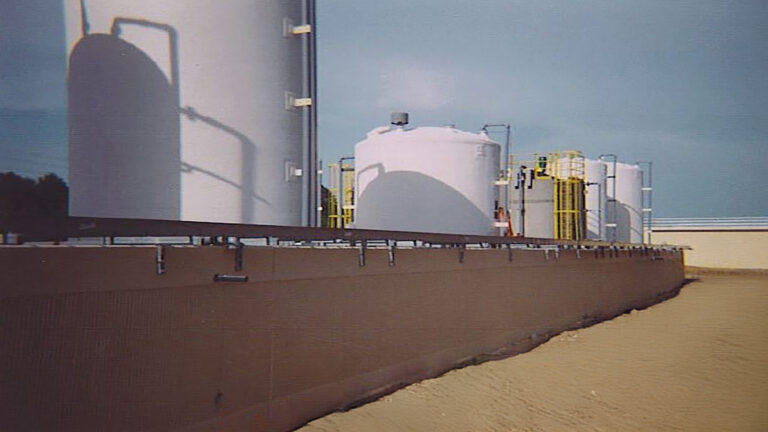Shell Oil Refinery, Pasadena, TX - masonry wall with industrial storage tanks behind it, Keeton Construction Services