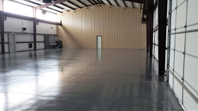 Open warehouse floor at United Laser Cladding in Cypress, TX by Keeton Construction Services, viewed from inside with a roll-up door at the far end