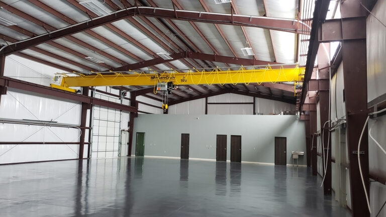 Interior of United Laser Cladding in Cypress, TX by Keeton Construction Services, showing an overhead bridge crane spanning the open bay