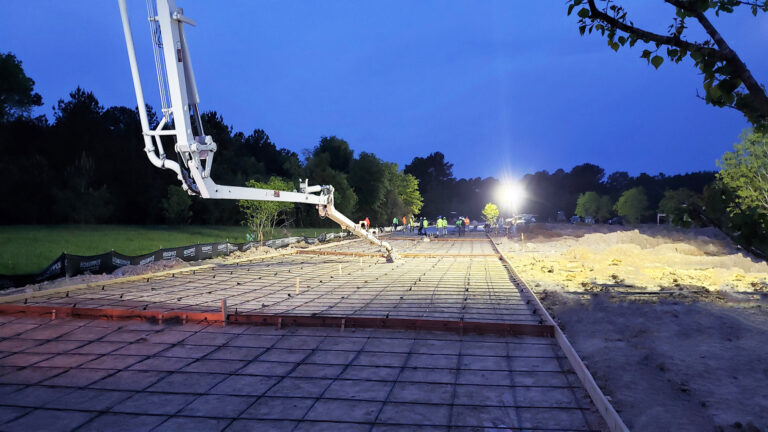 Nighttime concrete pour at United Laser Cladding in Cypress, TX by Keeton Construction Services, with a pump boom over the rebar grid and crew under work lights