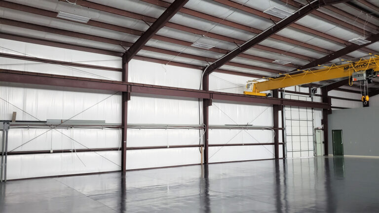 Interior of the United Laser Cladding facility in Cypress, TX by Keeton Construction Services, with an overhead bridge crane and open floor area