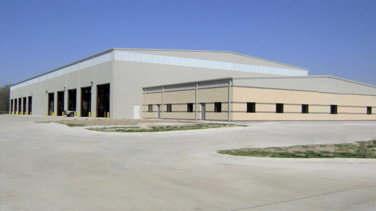 Corner exterior view of a metal building at Master Rig International in Houston, TX by Keeton Construction Services showing overhead doors and a masonry lower band