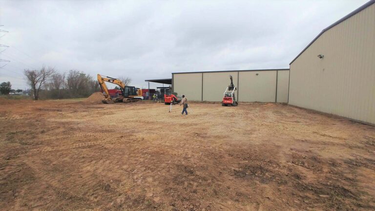 Precision Piping Products site work in progress in Houston TX by Keeton Construction Services, excavator and workers on bare dirt