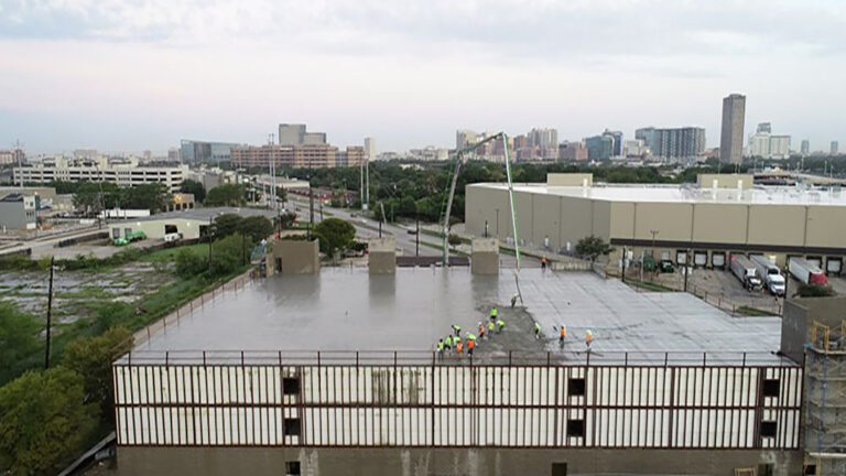 Aerial view of OST Storage Facility during construction in Houston TX by Keeton Construction Services, workers on roof deck with Houston skyline in background