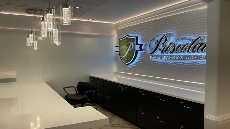 Reception desk with illuminated Prescolaire logo wall at Early Learning Academy Spring, built by Keeton Construction Services, Spring, TX