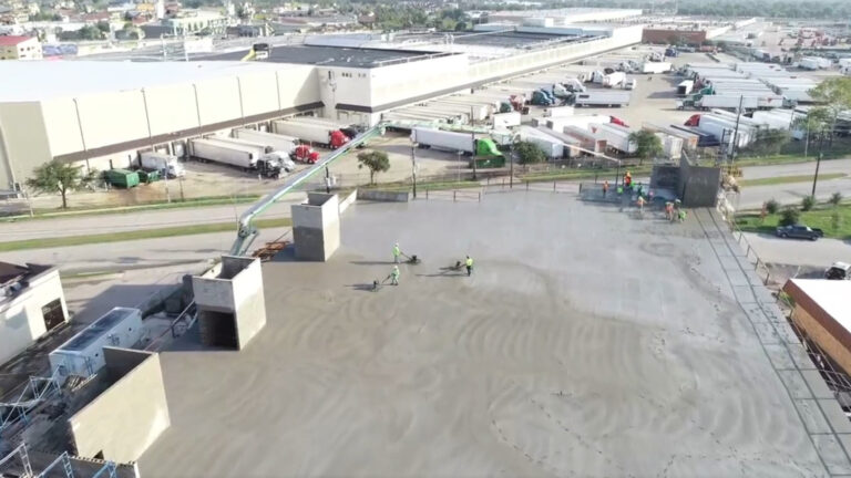 Aerial view of OST Storage Facility roof deck during construction in Houston TX by Keeton Construction Services, workers and concrete pump boom visible