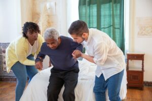 Person being assisted into bed in nursing home after Houston commercial construction completion