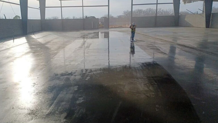 Worker applying floor coating inside the building during construction at Houston Signature Flight Support Hobby, TX - Keeton Construction Services