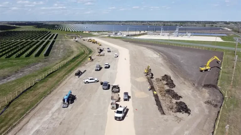 Aerial view of site work in progress at Axium Solar Farm in Alvin, TX, with excavators and trucks alongside solar panel rows, by Keeton Construction Services