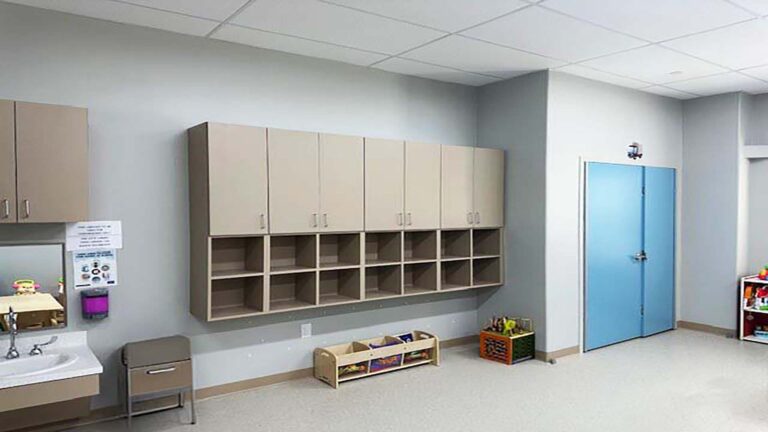 Little Texans Day Care Center interior room with wall-mounted cubbies, upper cabinets and a blue door, Conroe, TX - Keeton Construction Services