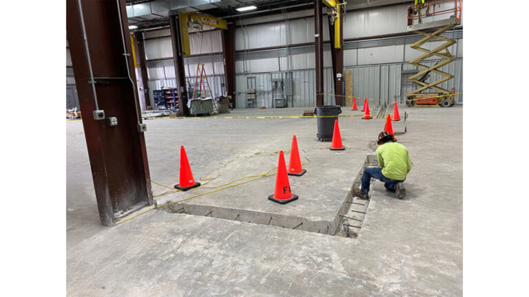 Worker performing floor work during construction at Oceaneering International Inc in Houston, TX, by Keeton Construction Services, with safety cones and lift equipment