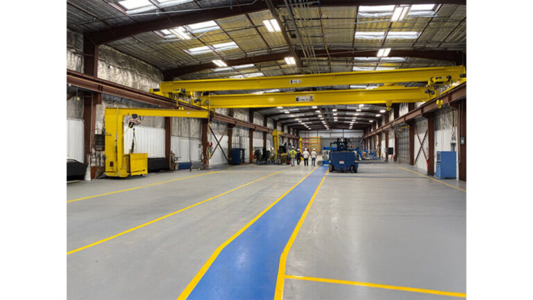 Interior of the Oceaneering International Inc facility in Houston, TX by Keeton Construction Services, with overhead crane and floor markings visible