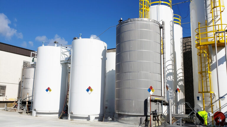 Univar Solutions Brisbane storage tanks by Keeton Construction Services, Houston TX — industrial tank farm with hazmat placards and yellow safety railings