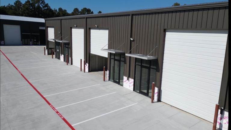 Exterior facade of Spring Cypress Business Park in Tomball TX showing overhead doors and glass entry doors on a metal building, Keeton Construction Services
