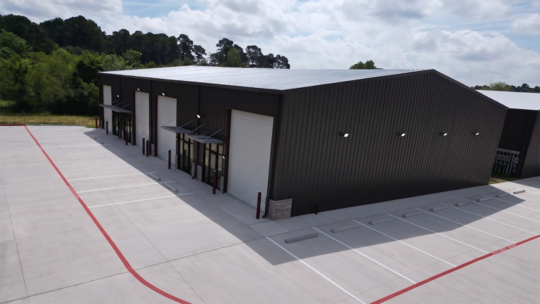 Close aerial view of a metal building exterior at Spring Cypress Business Park in Tomball TX with overhead doors and paved parking, Keeton Construction Services