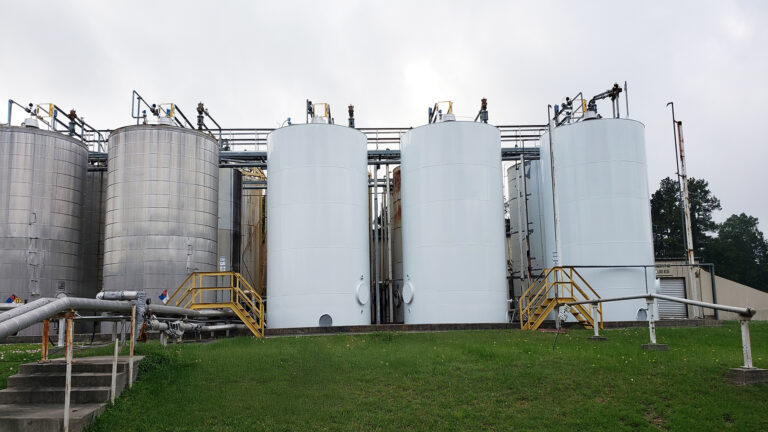 Univar Solutions Waller tank farm viewed from ground level, Waller TX - Keeton Construction Services project showing tanks with yellow safety stairs and piping