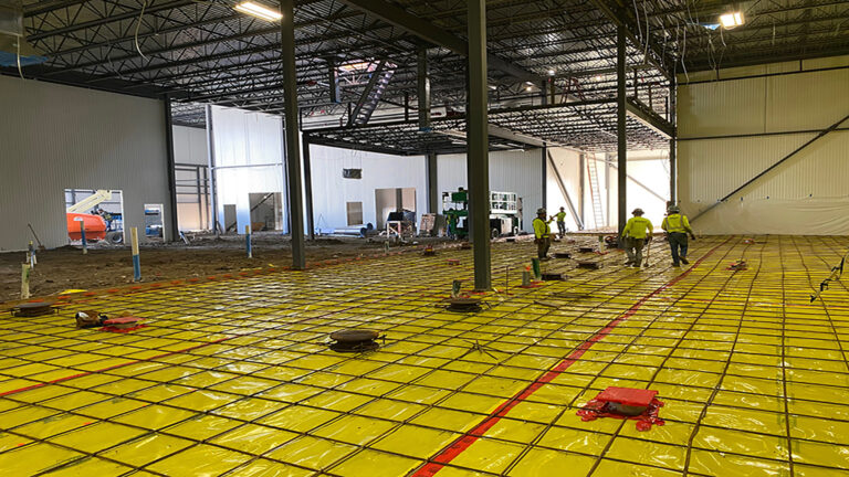 Interior view of the Gourmet Foods building during construction in Houston, TX with workers on the floor and structural framing overhead, by Keeton Construction Services