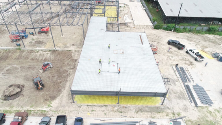 Aerial view of Gourmet Foods during construction in Houston, TX with workers on the roof deck and structural framing rising behind, by Keeton Construction Services