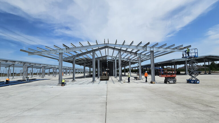 Lamar CISD Transportation Center Bus Canopies in Rosenberg TX - canopy framing during construction with workers and equipment on site, Keeton Construction Services